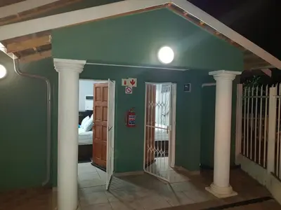 a room with green walls and white columns and a bedroom at Good 2 Go Guest House in Benoni