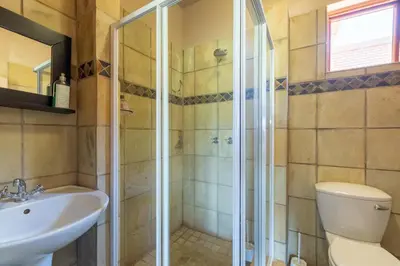 a bathroom with a shower and a toilet and a sink at Kareefontein 8 Bedroom Lodge IKH1 in Mabula