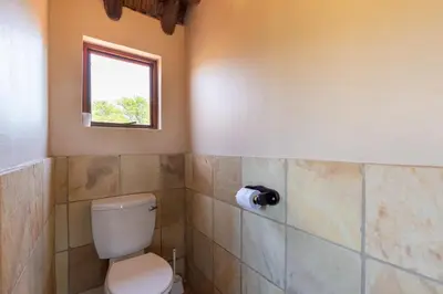 a bathroom with a toilet and a window at Kareefontein 8 Bedroom Lodge IKH1 in Mabula