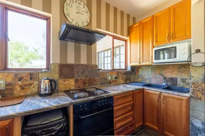 a kitchen with wooden cabinets and a clock on the wall at Kareefontein 8 Bedroom Lodge IKH1 in Mabula