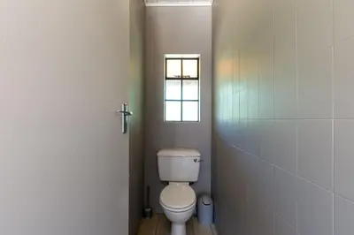 a bathroom with a toilet and a window at Kareefontein 8 Bedroom Lodge IKH1 in Mabula