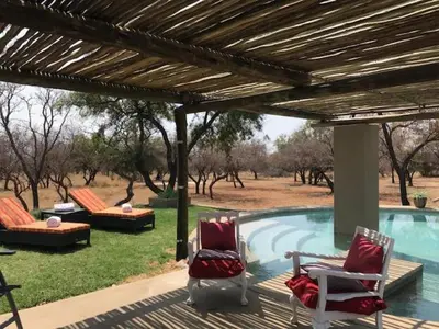 a patio with chairs and a swimming pool at Kareefontein 8 Bedroom Lodge IKH1 in Mabula