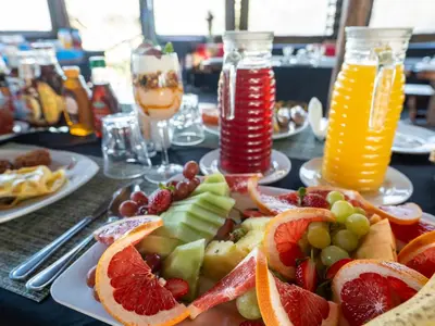 a plate of fruit on a table with two glasses of juice at Buffalo Rock Tented Camp in Hazyview