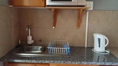 a kitchen counter with a sink and a microwave at Chariots Guest House in Polokwane