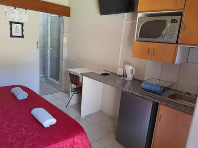 a small kitchen with a red bed in a room at Chariots Guest House in Polokwane
