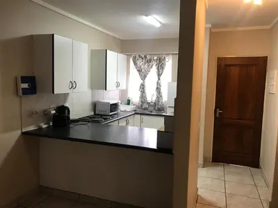 a kitchen with white cabinets and a black counter top at Apartments in Menlyn Maine, at Menlyn Place in Pretoria
