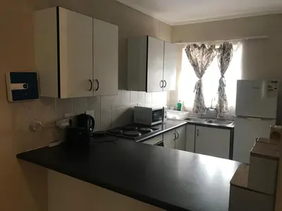 a kitchen with white cabinets and a black counter top at Apartments in Menlyn Maine, at Menlyn Place in Pretoria
