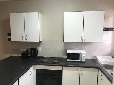 a kitchen with white cabinets and a stove and a microwave at Apartments in Menlyn Maine, at Menlyn Place in Pretoria