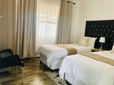 a bedroom with two beds and a chair and a window at Molas Luxury Accomodation in Ga-Mothiba