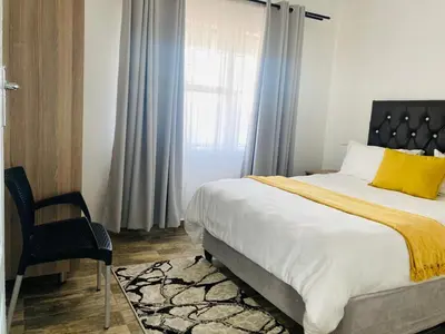 a bedroom with a bed and a chair and a window at Molas Luxury Accomodation in Ga-Mothiba