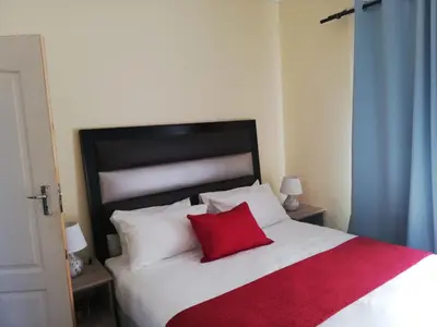 a bed with a red pillow on top of it at Molas Luxury Accomodation in Ga-Mothiba
