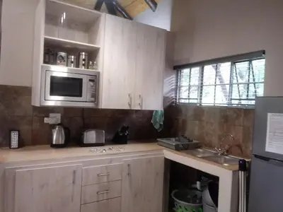 a kitchen with wooden cabinets and a microwave at Marloth Wild Fig Studio in Marloth Park