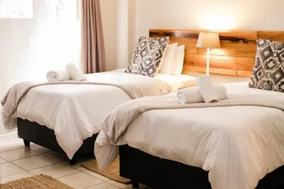a bedroom with two beds with white sheets at St George's Guest House in Tzaneen