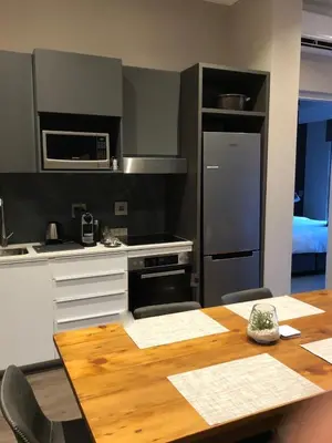 a kitchen with a table and a refrigerator and a stove at MENLYN MAINE - One Bedroom Penthouse - NO LOAD SHEDDING!! in Pretoria