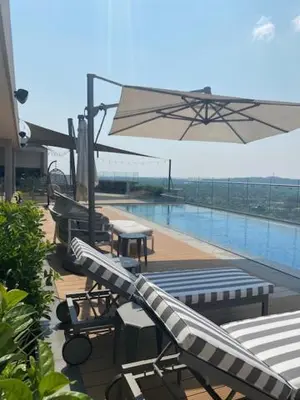 a patio with tables and chairs and an umbrella at MENLYN MAINE - One Bedroom Penthouse - NO LOAD SHEDDING!! in Pretoria