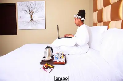 a woman sitting on a bed using a laptop at La Fiato Luxury Lodge in Dalmada AH