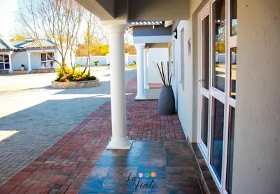 a brick walkway next to a building with columns at La Fiato Luxury Lodge in Dalmada AH
