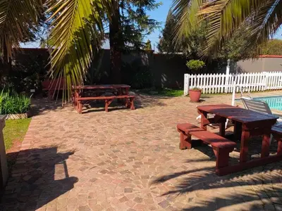 a patio with two picnic tables and a fence at Sibahlenomhlambi Guesthouse in Springs