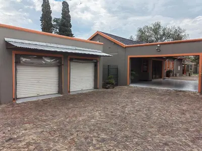 a house with two garage doors and a driveway at Sibahlenomhlambi Guesthouse in Springs