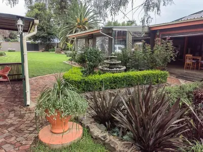 a garden with plants and a house at Sibahlenomhlambi Guesthouse in Springs