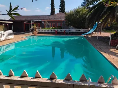 a swimming pool with a slide and a playground at Sibahlenomhlambi Guesthouse in Springs
