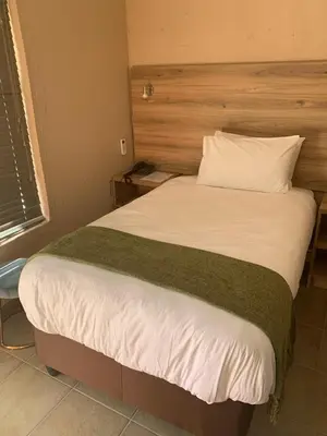 a bedroom with a large bed with white sheets at The Hill Lodge in Thohoyandou