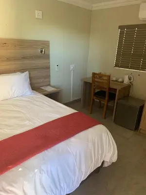a bedroom with a bed and a table and a desk at The Hill Lodge in Thohoyandou