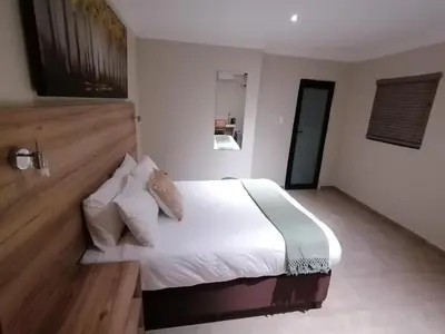 a bedroom with a large bed with white sheets and pillows at The Hill Lodge in Thohoyandou