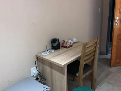 a wooden desk with a chair next to a wall at The Hill Lodge in Thohoyandou
