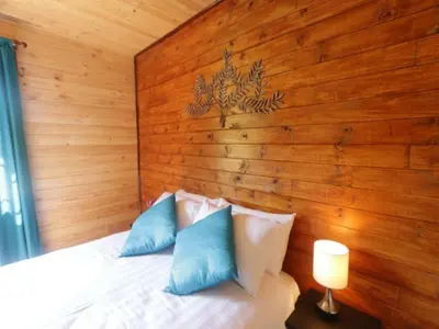 a bedroom with a wooden wall and a bed with pillows at Mountain Fly Fishing in Magoebaskloof