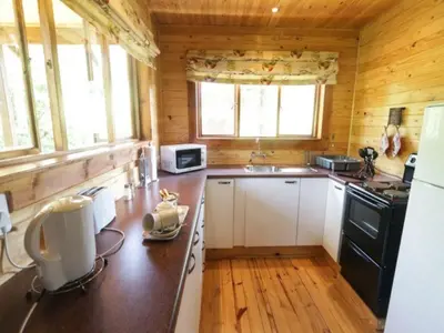 a kitchen with white cabinets and a black refrigerator at Mountain Fly Fishing in Magoebaskloof