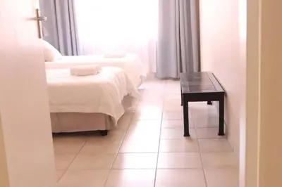 a room with two beds and a table and a window at Die Huis - Self Catering in Bela-Bela