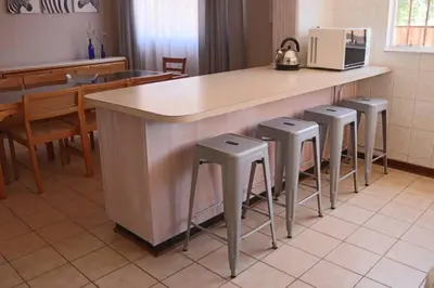 a kitchen with a counter and four stools at Die Huis - Self Catering in Bela-Bela