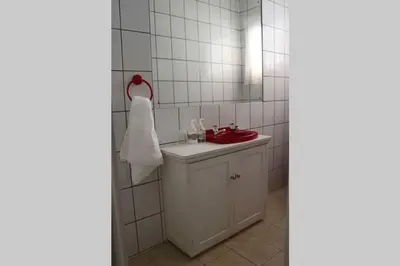 a bathroom with a red sink and a mirror at Die Huis - Self Catering in Bela-Bela