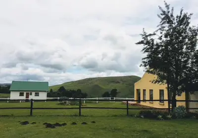a farm with a building and a tree in a field at Fly Shack in Dullstroom