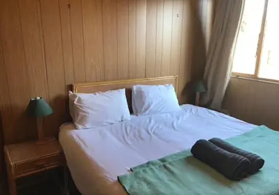 a bed with white sheets and pillows on it at Fly Shack in Dullstroom