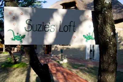a sign on a tree with a house in the background at Suzie's Loft - NUDE - SunEden Family Naturist Resort in Pretoria