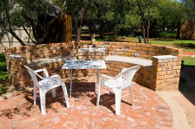 a brick wall with two chairs and a table and a table and two chairs at Suzie's Loft - NUDE - SunEden Family Naturist Resort in Pretoria