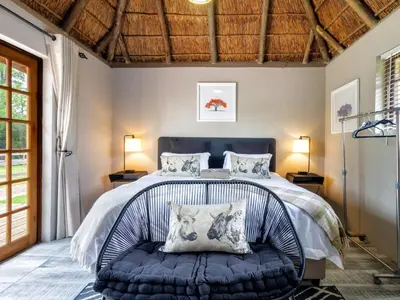 a bedroom with a large bed with a blue bench at The Horseshoe Guesthouse in Midrand