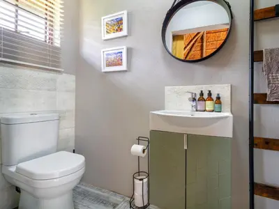 a bathroom with a toilet and a sink and a mirror at The Horseshoe Guesthouse in Midrand