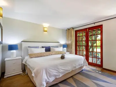 a bedroom with a large white bed and a red door at The Horseshoe Guesthouse in Midrand