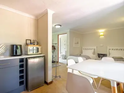 a kitchen and living room with a white table and chairs at The Horseshoe Guesthouse in Midrand