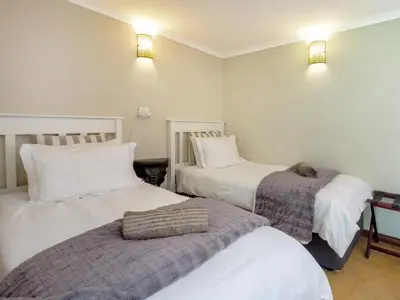 two beds in a room with white walls at The Horseshoe Guesthouse in Midrand
