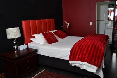 a bedroom with a large bed with a red headboard at Casa de Ross in Pretoria