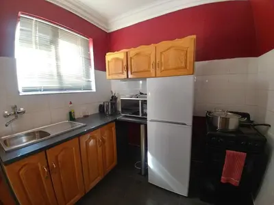 a kitchen with wooden cabinets and a white refrigerator at Casa de Ross in Pretoria