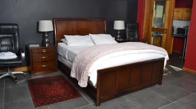 a bedroom with a large bed and two chairs and a desk at Casa de Ross in Pretoria