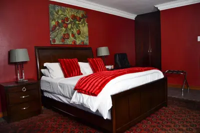 a bedroom with a large bed with red walls at Casa de Ross in Pretoria
