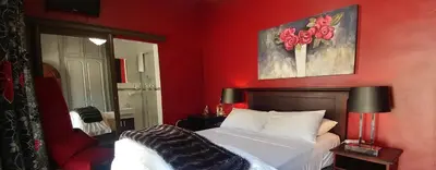 a bedroom with a bed and a red wall at Casa de Ross in Pretoria
