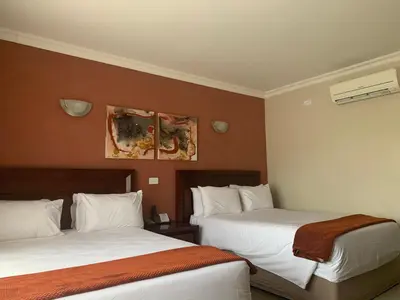 a hotel room with two beds and a painting on the wall at Royal Hotel in Polokwane