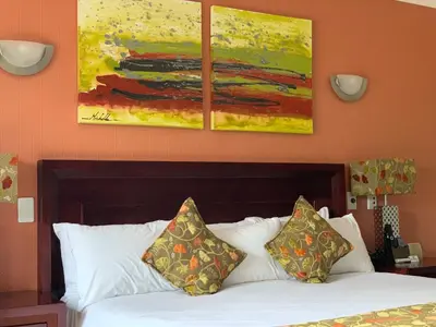 a bedroom with a bed with two paintings on the wall at Royal Hotel in Polokwane